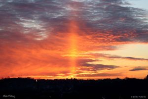 Zalazak Sunca s oblacima i jasno vidljivim okomitim stupom narančaste svjetlosti