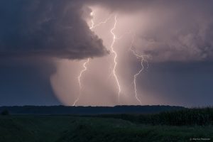 Noćni pogled na tri munje koje osvjetljavaju kišnu zavjesu