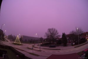 Širokokutna fotografija gradske ulice s neobično ljubičastim nebom, a boju je poprimio i krajolik