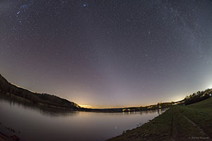 Noćno nebo iznad jezera sa zodijačkom svjetlošću kao blijedim sjajem koji se proteže po sredini fotografije