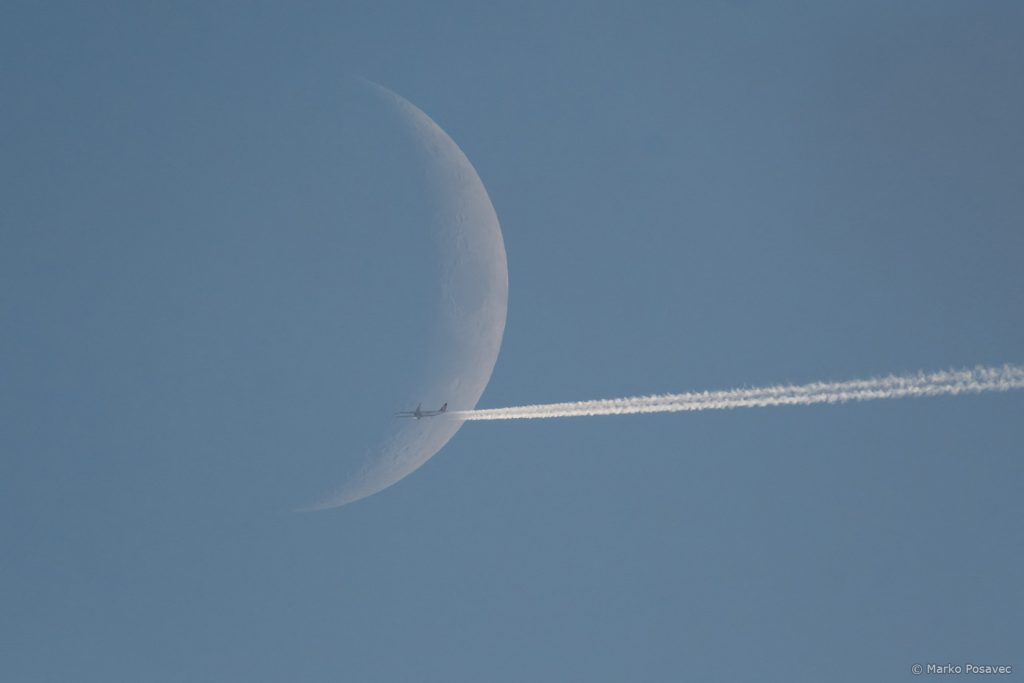 Daleki avion prelazi preko Mjesečevog srpa
