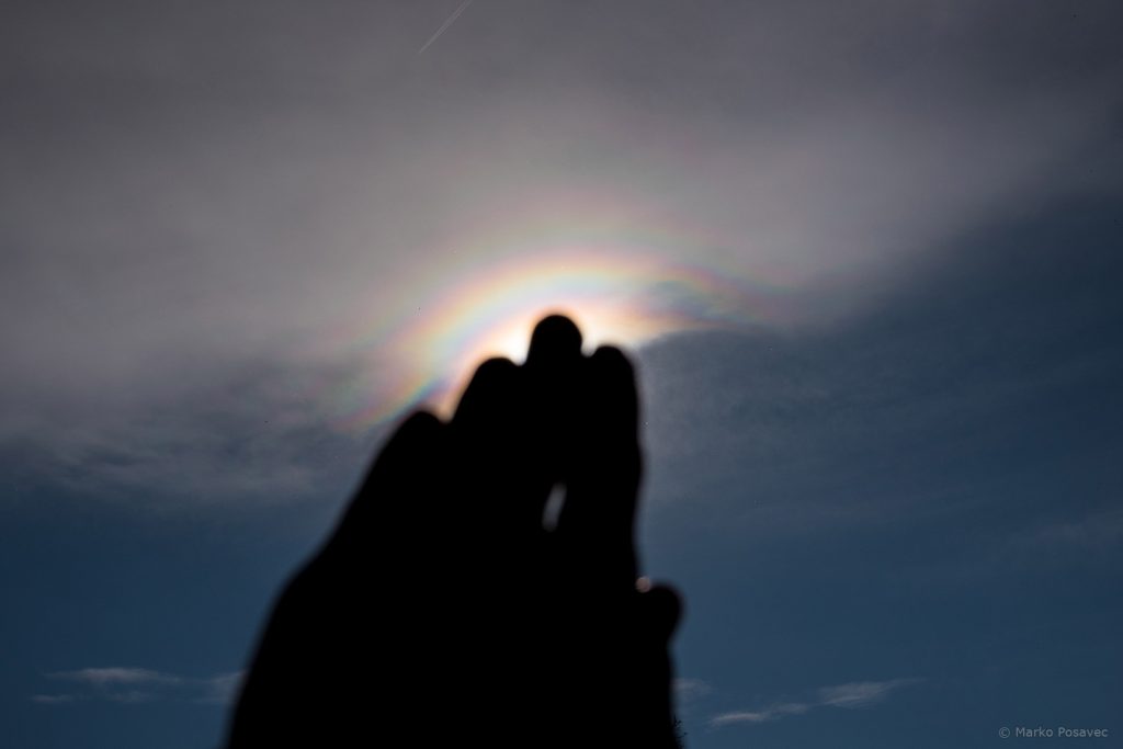 Sunce zaklonjeno dlanom ruke sa šarenim prstenovima