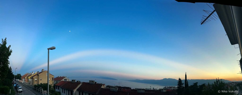 Široka panoramska fotografija svijetlih zraka koje se pružaju preko neba od zapada prema istoku